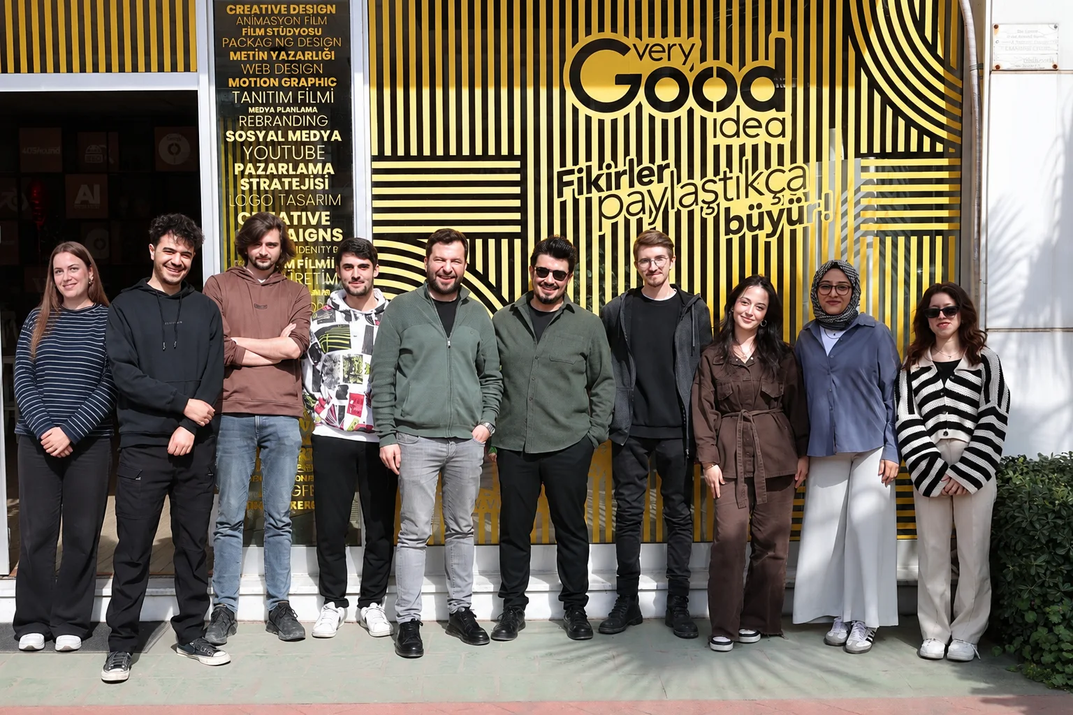 Very Good Idea ekibi ajansın sarı çizgili cephesi önünde