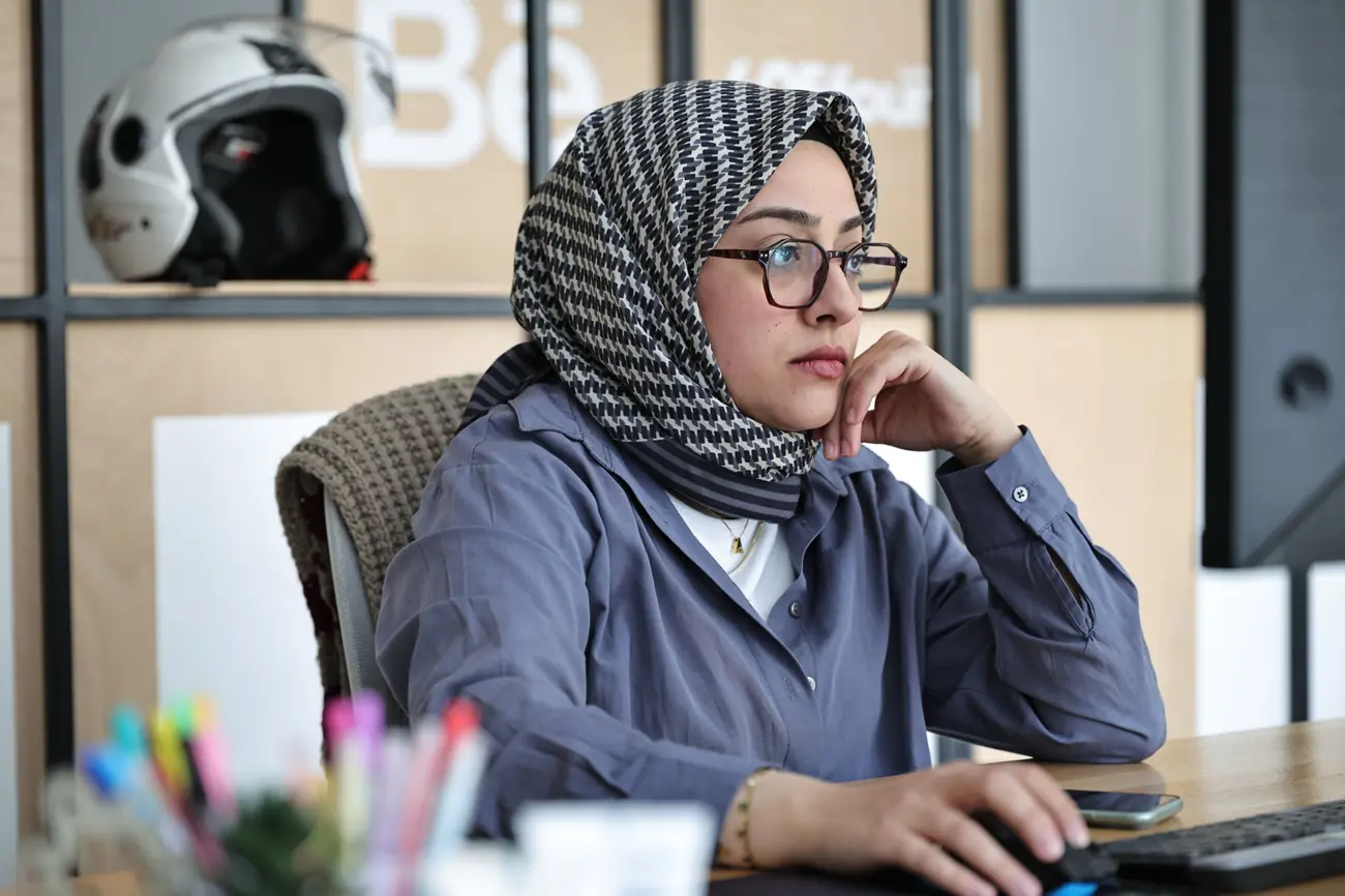 Bir ekip üyesi masasında düşünceli biçimde ekrana bakarken